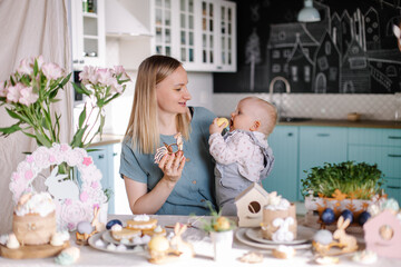 family with child celebrates easter. Happy mom and baby at the festive table. Easter eggs and cake. Set table with decor for a traditional dinner. Spring Christian holiday. Happiness laughter mood
