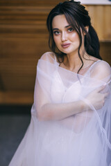 Naklejka premium Beautiful attractive bride in a wedding dress wrapped in a veil. Delicate makeup. morning meeting.