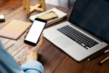 Mockup image of a woman using smartphone with blank screen on wooden table.