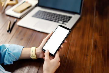 Mockup image of a woman using smartphone with blank screen on wooden table.