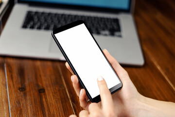 Mockup image of a woman using smartphone with blank screen on wooden table. Close up photo of female hands holding mobile phone vertically