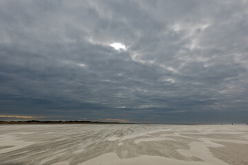 Storm blowing sand over the vast beach under a dark sky in winter
