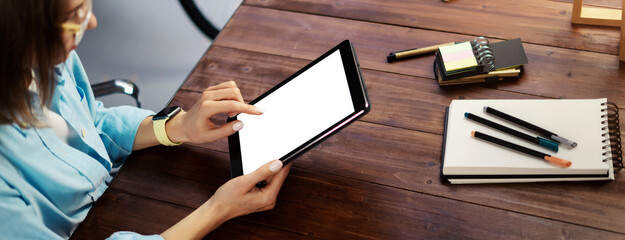 Mockup image of a woman using digital tablet with blank screen on wooden table. Close up photo of female hands holding device vertically