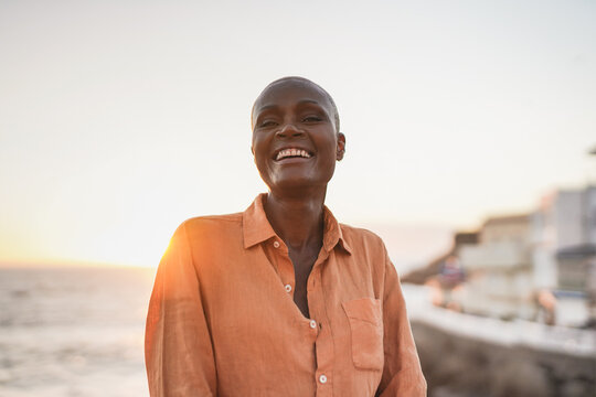 Happy senior african woman looking in camera - Beach and sunset in background