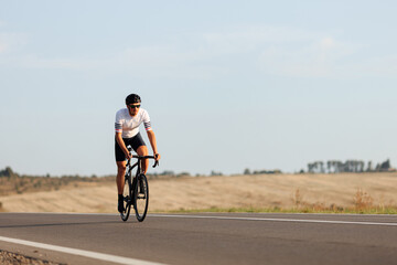 Fototapeta na wymiar Sportsman in helmet riding bike among countryside