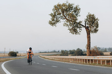 Muscular man riding bike with high speed on road