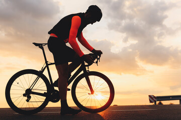 Muscular cyclist standing on road with his bike for racing