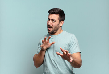 young handsome adult man feeling disgusted and nauseous, backing away from something nasty, smelly...