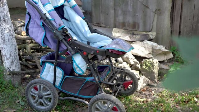 old baby carriage,broken blue stroller near the stone stands