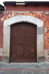 Fototapeta na wymiar wooden door in colonial type house stone frame close up in old street