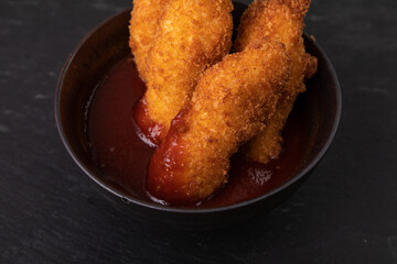 Crispy golden fish fingers in a bowl of sauce