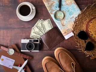 Top view of accessories for tourist to travel in vacation on brown theme, Camera with money and outfit and coffee and map with magnifying glass. Travel trip concept, on brown wooden background. © EEarth