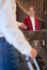A pleasant female receptionist servicing a guest at the hotel. Tourism, business, hotel