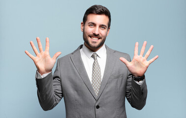 young adult handsome businessman smiling and looking friendly, showing number ten or tenth with...