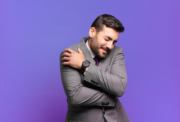 young adult handsome businessman feeling in love, smiling, cuddling and hugging self, staying...