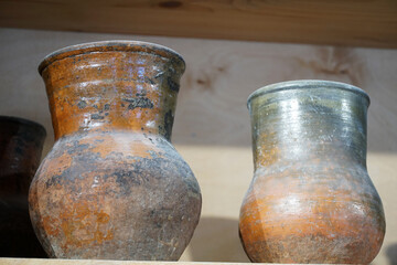 Ancient clay jugs on a rack of a pottery workshop