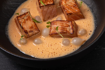 Cooked salmon peaces in creamy sauce decorated with micro greens