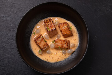 Cooked salmon peaces in creamy sauce decorated with micro greens