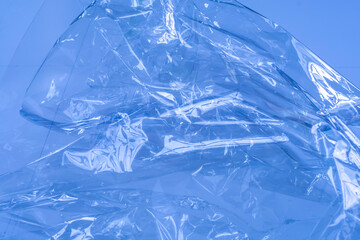 Crumpled transparent cellophane film on a blue background.