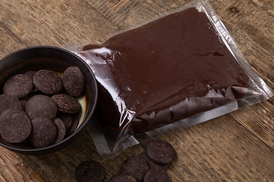 Chocolate Sauce In A Vacuum Sealed Plastic Bag With Chocolate Buttons In A Bowl