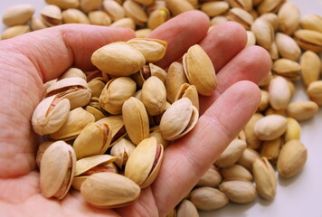 Hand holding pistachio nuts. Healthy food and snacks. Nuts, pistachios. Background of nuts. Top view or flat lay. Tasty pistachios as background. Walnut, pistachios, almonds, hazelnuts and cashews.