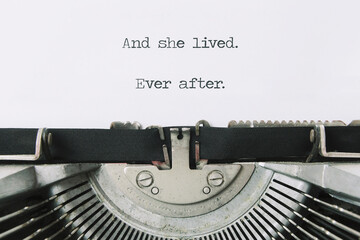 The ending phrase And she lived, ever after, printed on a paper page inside an old vintage...