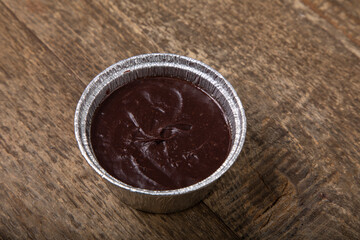 Melted milk chocolate in foil pot on a wooden table