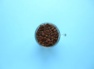 Coffee beans in a transparent glass. Coffee. Blue background. View from above. Place for the text. 