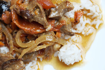 rice and meat goulash with vegetables on a white plate close-up
