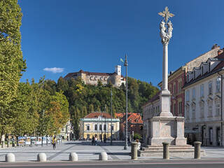 Fototapeta na wymiar Ljubljana, Slovenia. Congress Square with Holy Trinity Column on the foreground and Slovenian Philharmonic Building at the opposite side on the background of Ljubljana Castle.