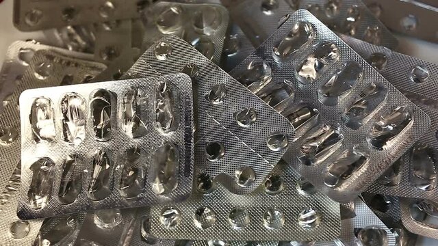 Empty packages of pills, capsules, lozenges fall into a pile. Real time, average shot, indoor
