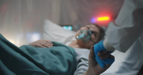 Doctor in gloves and ppe suit holding hands of sick covid-19 aged lady lying in bed - Powered by Adobe