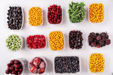 Frozen berries and vegetables in plastic boxes isolated on white background.