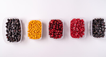 Frozen berries in plastic boxes isolated on white background.