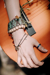 Hippie female hands with boho wood beaded bracelets holding guitar part