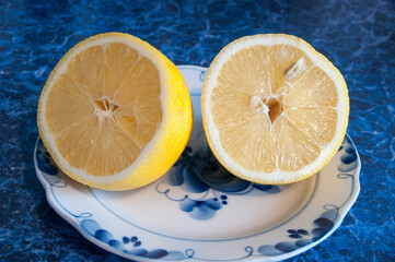 Two halves of a sliced yellow lemon on a white saucer. Background, design.