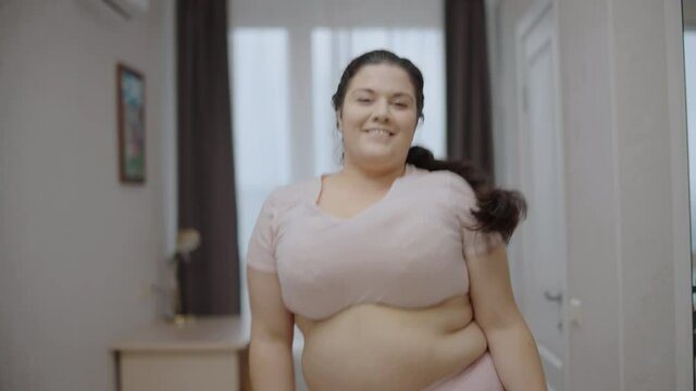 Active overweight woman feeling happy dancing at home, body positive, confidence