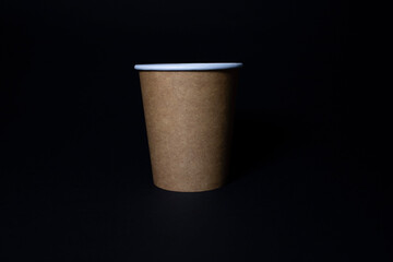 Disposable eco-friendly food packaging. Brown food cup made of kraft paper on a black background.
