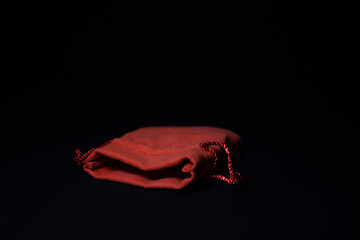 Red suede bag for costume jewelry on a black background.