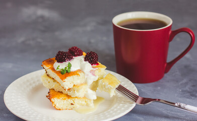Cottage cheese casserole on a white plate and tea in a burgundy cup on a gray background