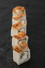 Tasty dragon sushi rolls with eel on black surface