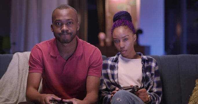 Bored young family portrait of dating man with woman holding joysticks browsing different games chossing favorite. Home entertainment.