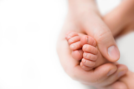 Feet of the newborn in the hands of mom close up. Mom and her child. A beautiful conceptual image of motherhood.