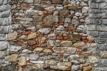 The wall is made of different stones. Stone background.