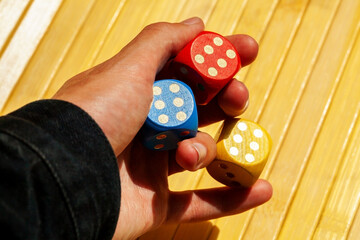 Lucky gambler hand holding three colorful shiny game dice showing number six. Multiple dice show 6,...