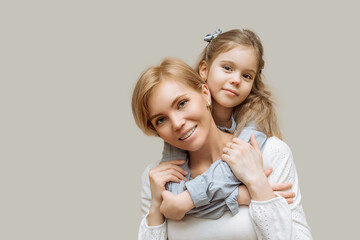 the concept of maternal love and care. mom and little daughter hug on gray background copy space happy family, parenthood