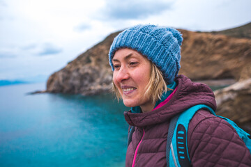 Portrait of a smiling girl in a knitted hat while walking along the sea coast