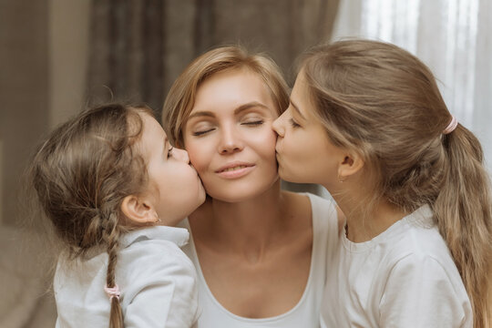 the concept of maternal love and care. children kiss their mother on the cheek. happy mom with kids
