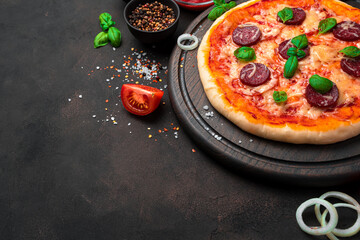 Fresh, delicious pizza and ingredients on a brown background. Top view with copy space.