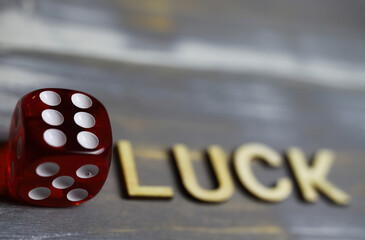 Closeup of isolated red dice cube face showing number six, blurred word text luck background (focus...